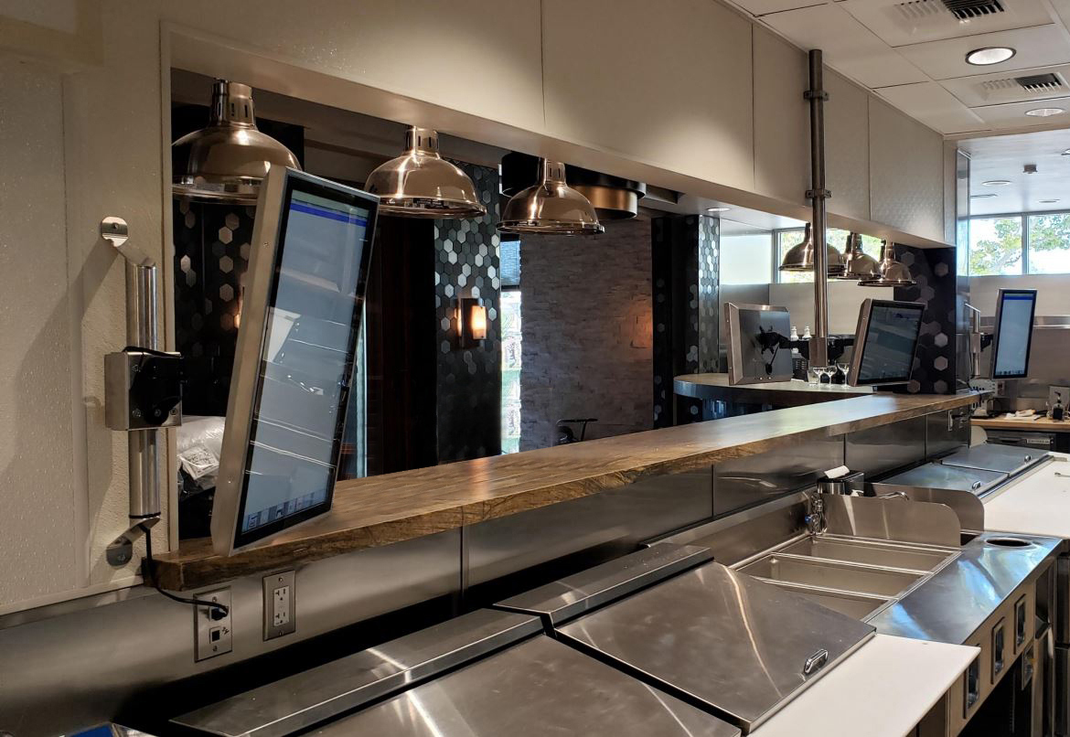 Multiple Kitchen Armor kitchen display screens mounted along a commercial prep line