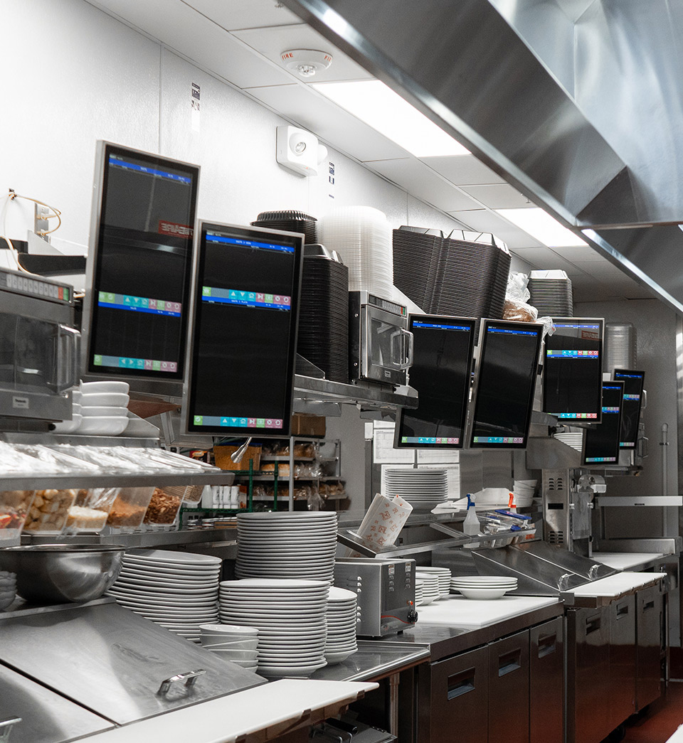 Kitchen Armor KDS screens deployed across a high-volume restaurant cook line